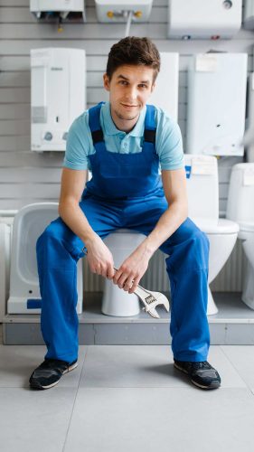 plumber-in-uniform-sitting-on-toilet-in-plumbering-RT6982P